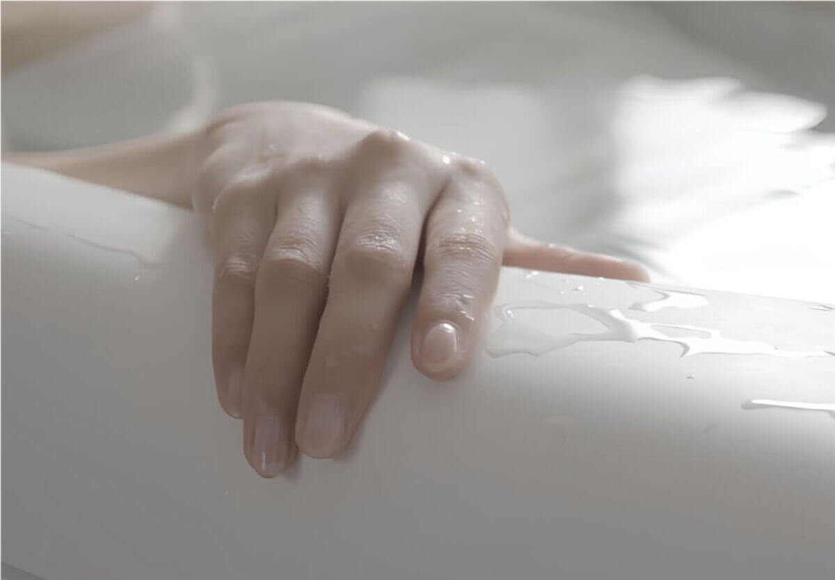 入浴中のリラックス感を高める、なめらかで保温性の高いトクラスのバスタブに手を添える様子