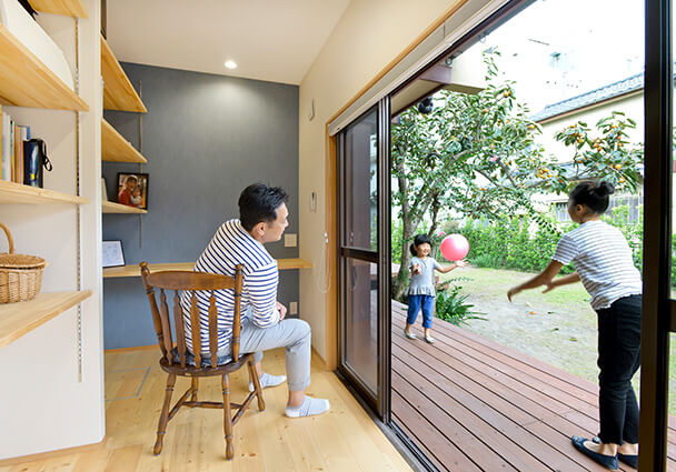 庭に面したウッドデッキと繋がる書斎スペース。子どもたちの遊びを見守る父親