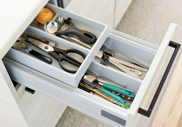 キッチンの浅型引き出し収納。カトラリーや調理器具が整理された仕切り付きの収納例。