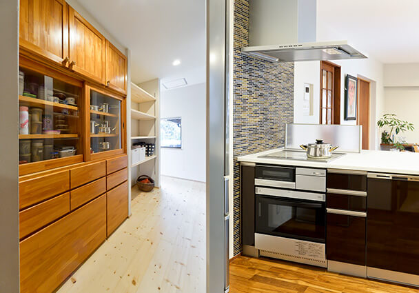 大容量の木製カップボードとパントリーへの動線。和の面影を残すキッチン収納