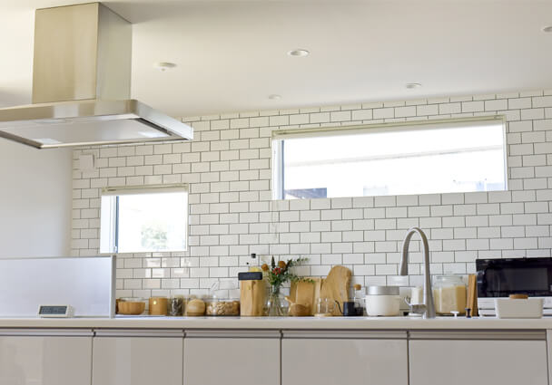 サブウェイタイルの壁と木製カウンター、キッチンの収納スペースと調理器具のディテール