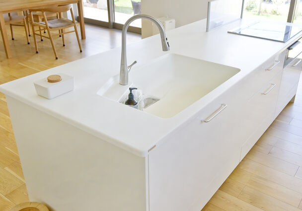 白で統一されたアイランドキッチンのシンク周り、シンプルで清潔感のあるLDK