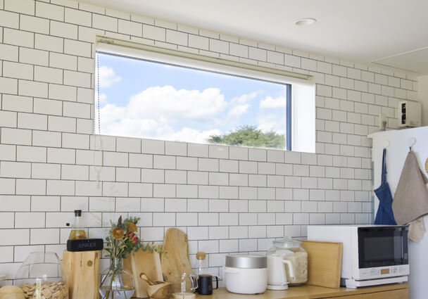 キッチンのタイル壁と横長の窓、明るい光が差し込む開放的なLDK