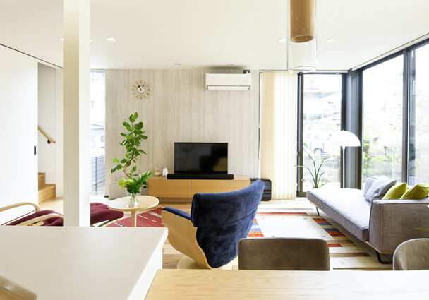 自然光が差し込むLDKのリビングスペース。テレビボードとおしゃれなソファ、観葉植物。