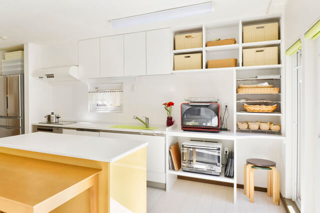 パンこね台のあるスタジオ風キッチン全体。家電やカゴを使った見せる収納。明るく広い作業スペース。