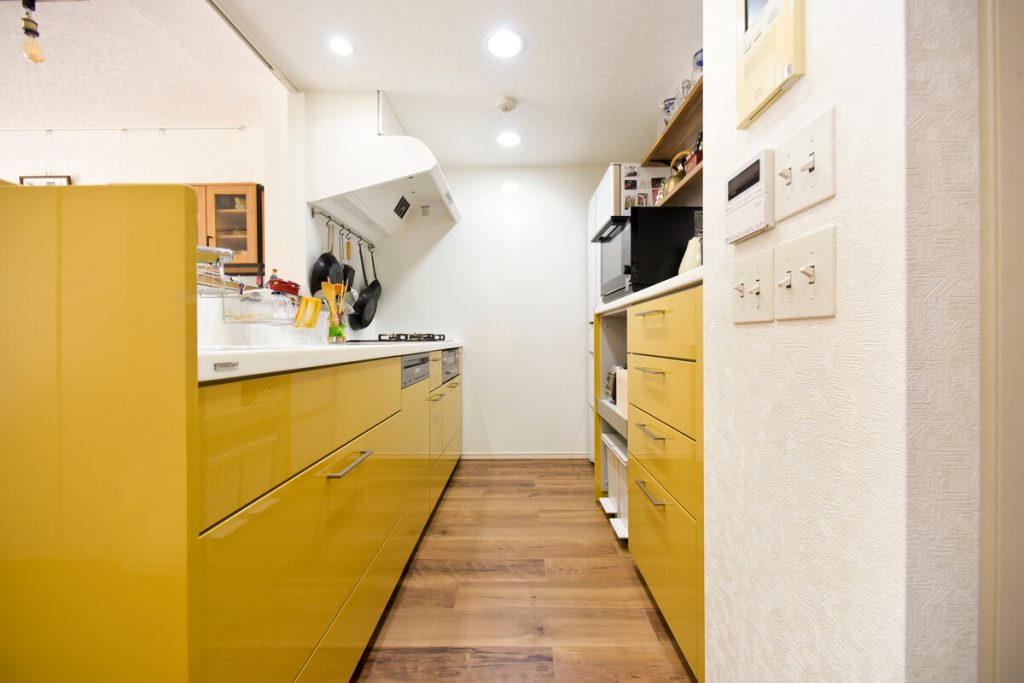 鮮やかなマスタードイエローが目を引くトクラスのシステムキッチン。背面収納も同色で統一したこだわりの空間。