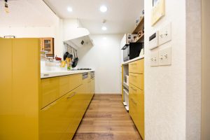 鮮やかなマスタードイエローが目を引くトクラスのシステムキッチン。背面収納も同色で統一したこだわりの空間。