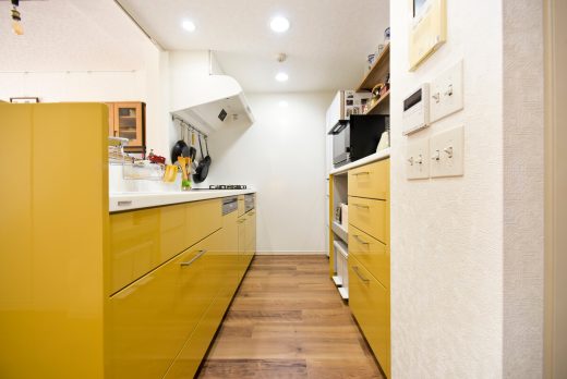 鮮やかなマスタードイエローが目を引くトクラスのシステムキッチン。背面収納も同色で統一したこだわりの空間。