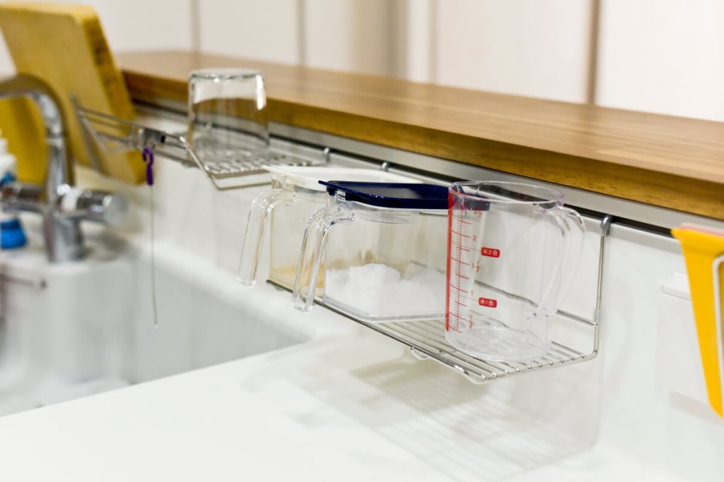 トクラス独自のハイバックカウンター。ハンガーアイテムを使って調味料や計量カップを「浮かせる収納」にした様子。