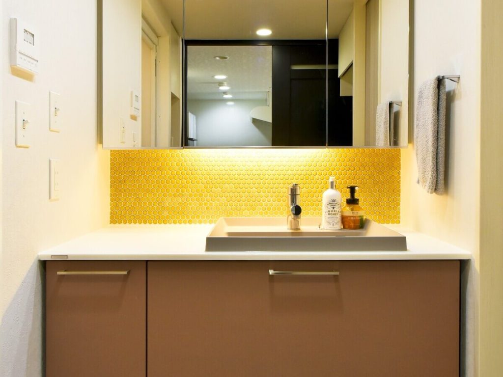 トクラスの洗面化粧台「Noare（ノーレ）」正面。大きな三面鏡とテラコッタの扉、黄色のタイルが調和したドレッサー空間。