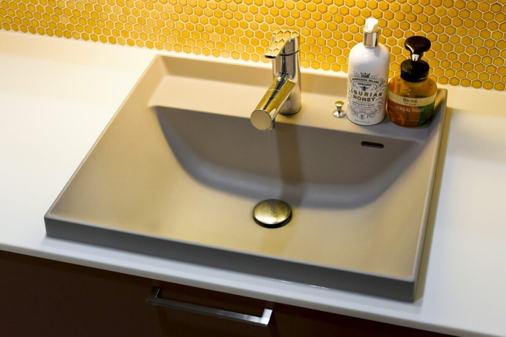 異国情緒を感じさせるイエローのハニカムタイルと、トクラス「Noare（ノーレ）」のスタイリッシュな洗面ボウル。