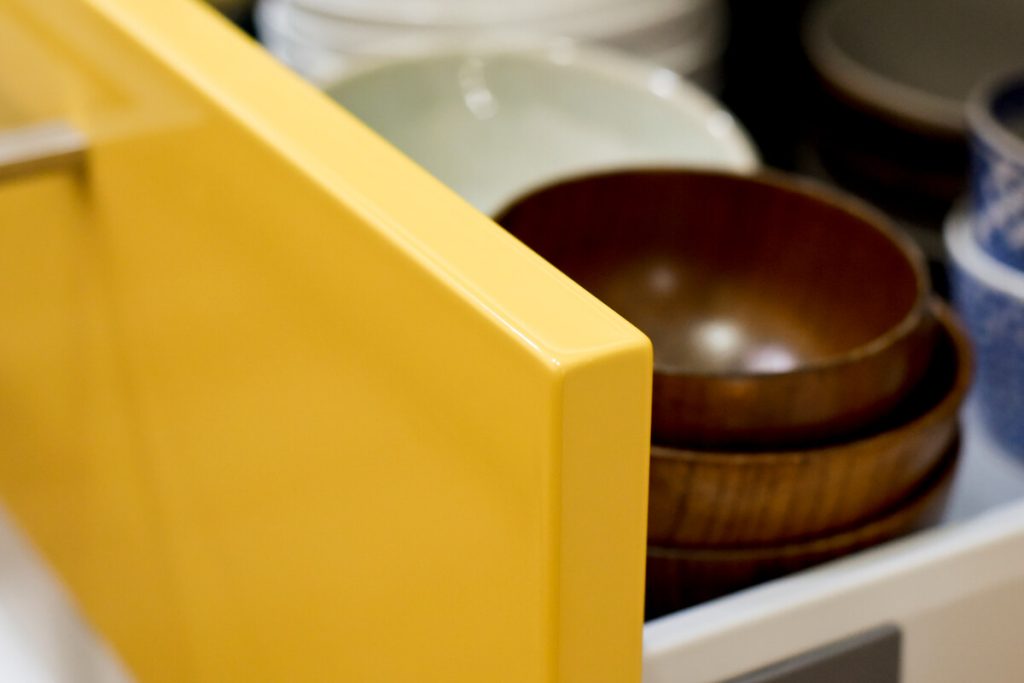 トクラスキッチンの「深支子（こきくちなし）」色の扉。引き出しにはお気に入りの木製食器が収納されている様子。