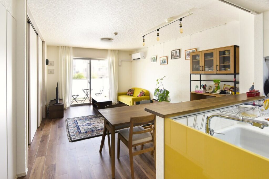 黄色のキッチンがアクセントになった、明るく開放的なリノベーションマンションのLDK全景。