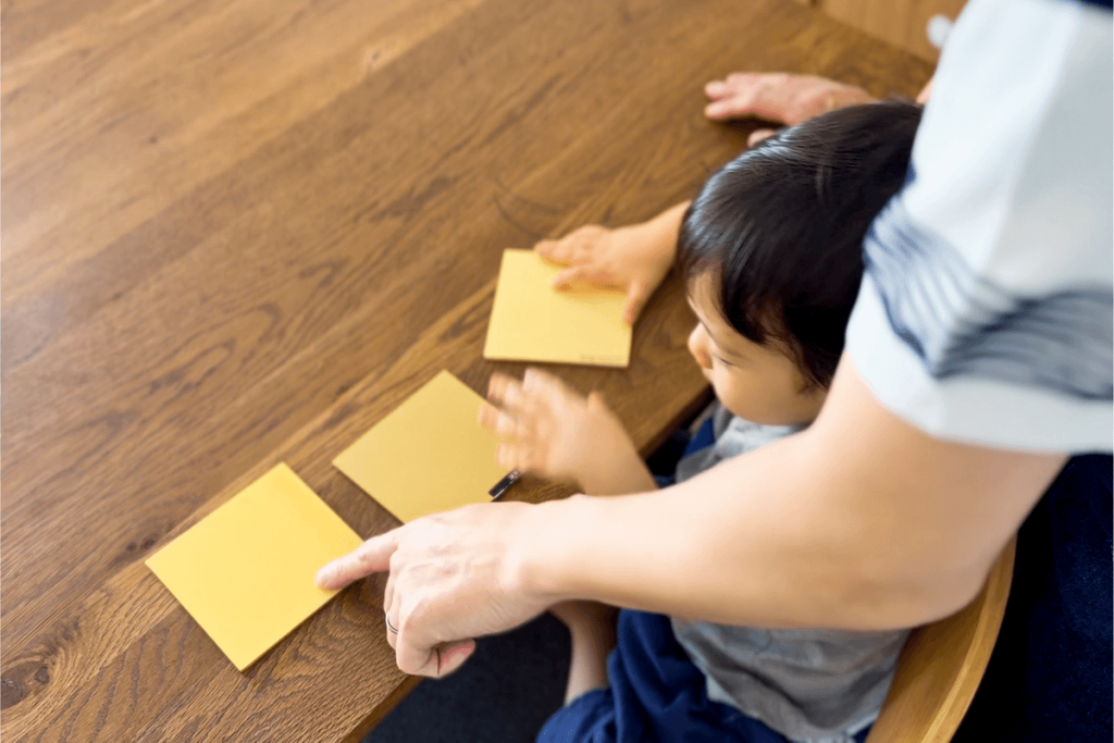 木のぬくもりを感じるダイニングテーブルで、親子が触れ合う穏やかな日常のひとコマ。