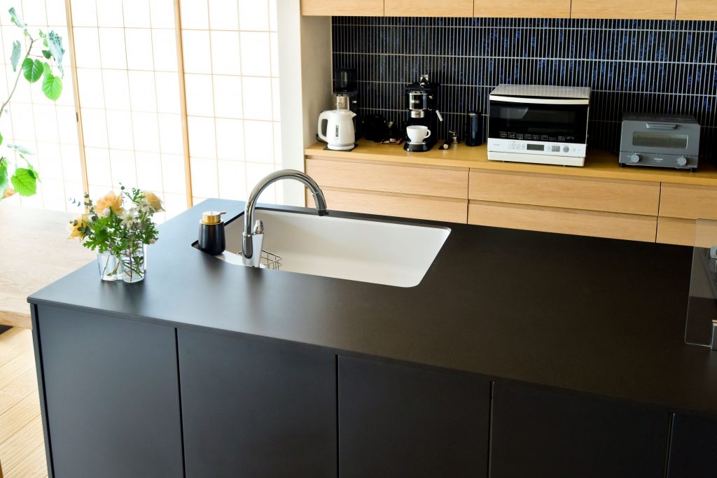 白と黒のシンプルさが美しいアイランドキッチンのシンク周り。長く愛用できるタイムレスな機能性。
