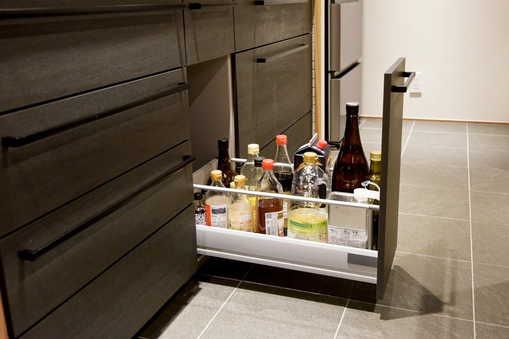 和風建築の住まいに合わせたダークカラーのキッチン。調理に必要な調味料を効率よく収納した引き出し。