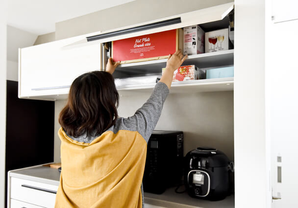 キッチンをすっきり見せる、吊り戸棚に収められたホットプレートなどの調理器具収納。
