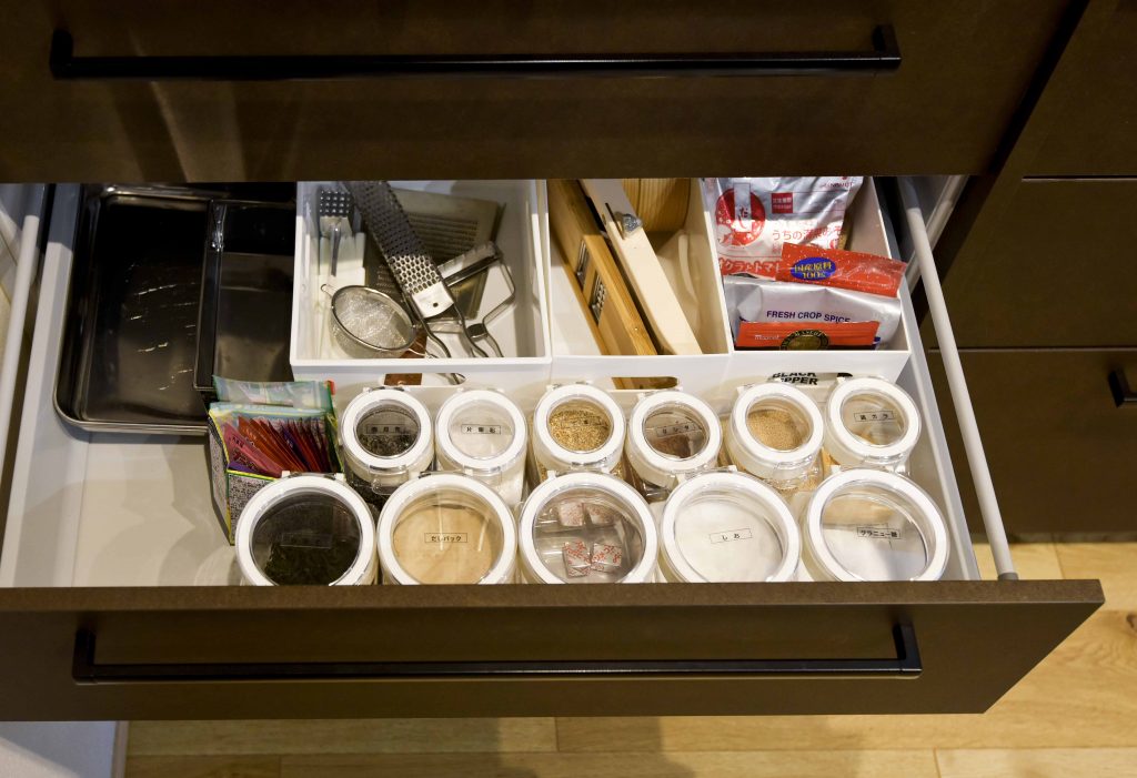 親子世帯の調理器具や調味料をまとめて収納できる、使いやすく整理された引き出し。収納充実のキッチンの実例。